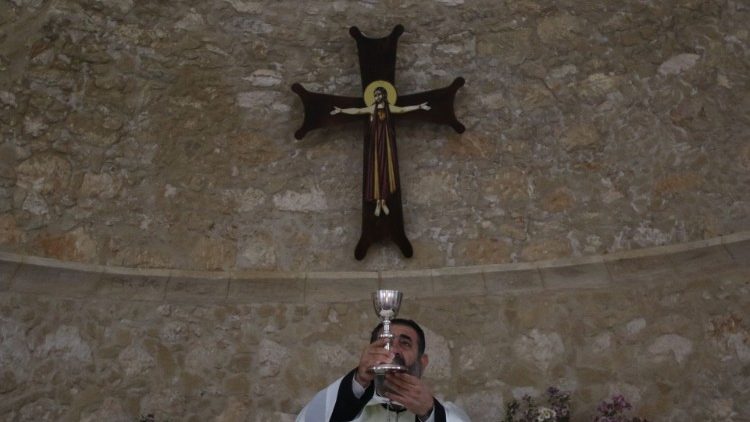A Maronite priest raises the chalice at the Church of St. George in Kormakitis