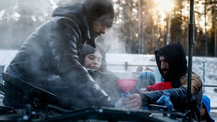 Migrants collect hot water outside a logistics center on the Belarusian-Polish border