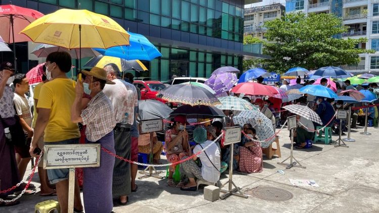 People line up outside a bank to withdraw cash, in Yangon, Myanmar.