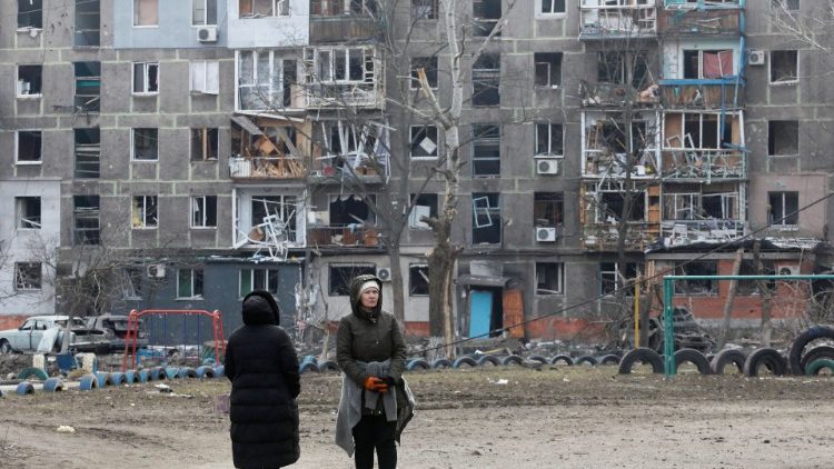 Civilians walk outside a damaged building in Mariupol, Ukraine