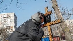 A woman kisses a cross on the grave of her mother killed by shelling in Mariupol