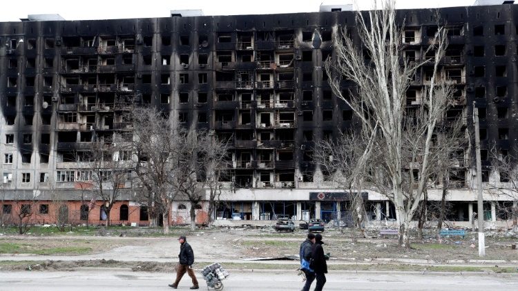 Moradores locais passam por um prédio queimado durante o conflito Ucrânia-Rússia na cidade portuária de Mariupol, no sul da Ucrânia, em 4 de abril de 2022 REUTERS/Alexander Ermochenko/Foto de arquivo