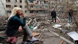 Una donna e un uomo tra le macerie di palazzi distrutti a Mariupol