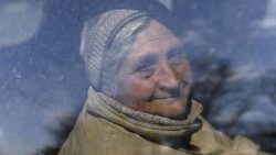 Ucraniana idosa sorrindo, depois de ser resgatada da cidade de Karkhiv, bombardeada pelos russos. (REUTERS/Ricado Moraes)