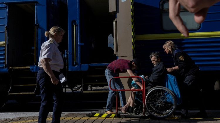 Ukrainian Emergency Service members help an elderly man to board a train during an evacuation effort from war-affected areas of eastern Ukraine