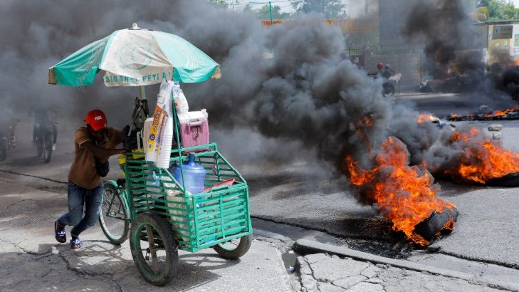 Un commercant passe outre un barrage incendié le 13 juillet dernier à Port-au-Prince.