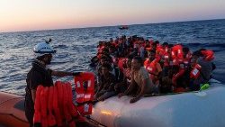 Un membre de l'équipage de Sea-Watch donne des gilets de sauvetage à des migrants sur un bateau pneumatique en mer Méditerranée, le 23 juillet 2022