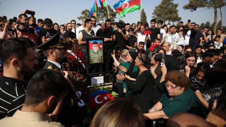 अजरबैजान में एक पुलिसबल की मौत पर अंतिम संस्कार के लिए एकत्रित लोग
