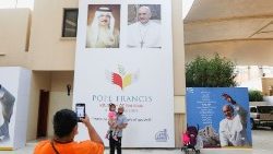 A visitor take photo in front of welcome banner for Pope Francis at Sacred Heart Catholic Church in Manama