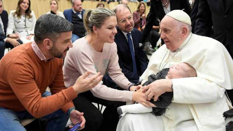 Ferenc pápa a kihallgatás során karján egy kisgyermekkel    