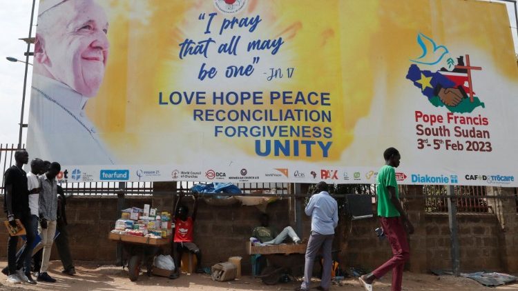 Sul-sudaneses junto a um outdoor durante os preparativos para receber o Papa Francisco em Juba. REUTERS/Thomas Mukoya