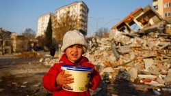 Uma criança segurando um recipiente de plástico olha em meio aos escombros, após um terremoto mortal em Kahramanmaras, Turquia, 14 de fevereiro de 2023. REUTERS/Suhaib Salem