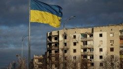 Ukraińska flaga powiewa w pobliżu budynków nadniszczonych w wyniku rosyjskich ostrzałów, Borodzianka, obwód kijowski, 15 lutego 2023