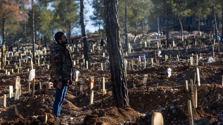 A man surrounded by tombs in a large graveyard in the aftermath of the earthquake in Kahramanmaras, Turkey