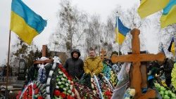 Ludzie odwiedzający groby swoich bliskich w Buczy w rocznicę wybuchu pełnoskalowej wojny na Ukrainie, 24 lutego 2023