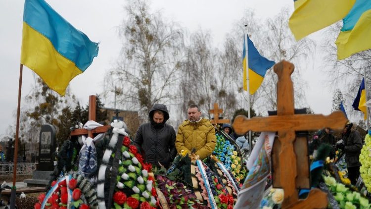 Ludzie odwiedzający groby swoich bliskich w Buczy w rocznicę wybuchu pełnoskalowej wojny na Ukrainie, 24 lutego 2023