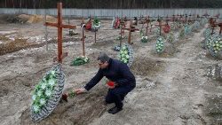 Varias personas visitan las tumbas de personas no identificadas, en un día del primer aniversario del ataque de Rusia a Ucrania, en Bucha.