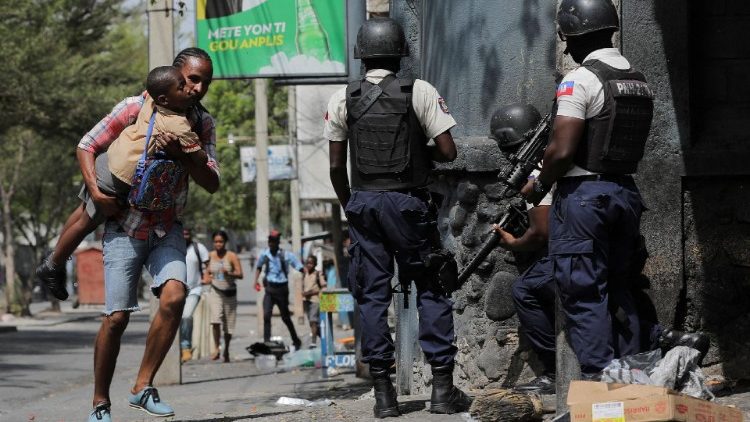 A man carries his son as they search for cover amid gang violence in Port-au-Prince