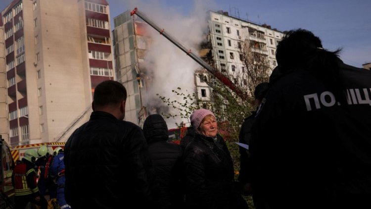 Pessoas ficam perto de um prédio residencial fortemente danificado atingido por um míssil russo enquanto equipes de resgate trabalham, em meio ao ataque da Rússia à Ucrânia, na cidade de Uman, região de Cherkasy, Ucrânia, 28 de abril de 2023. REUTERS/Carlos Barria