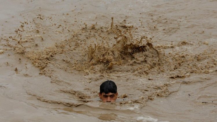 FILE PHOTO: A man swims in flood waters while heading for a higher ground, following rains and floods during the monsoon season in Charsadda