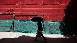 Extreme Hitzewelle über Europa - eine Person schützt sich mit einem Regenschirm vor der Sonne