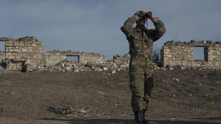 FILE PHOTO: An ethnic Armenian soldier looks through binoculars as he stands at fighting positions near divided Taghavard village in Nagorno-Karabakh region