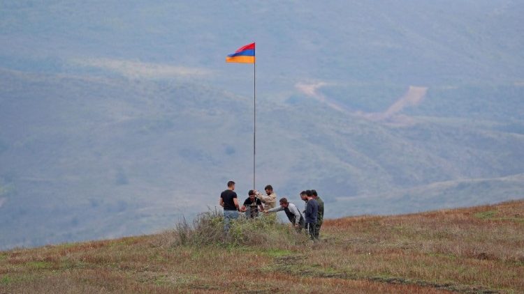 Men install an Armenian flag next to a checkpoint on the road leading to Nagorno-Karabakh near Kornidzor