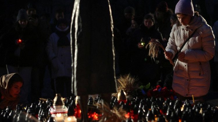 Uma mulher coloca espigas de trigo em um monumento às vítimas do Holodomor durante uma cerimônia em comemoração à fome de 1932-33, em que milhões morreram de fome, em Kiev, Ucrânia, em 25 de novembro de 2023. A cerimônia ocorre durante o ataque da Rússia à Ucrânia. REUTERS/Sofia Gatilova