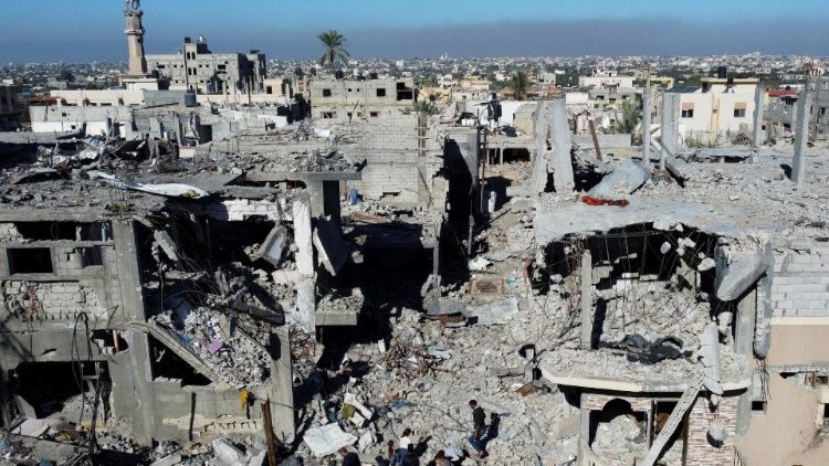 Palestinians walk among the rubble, as they inspect houses destroyed in Israeli strikes, at Khan Younis refugee camp