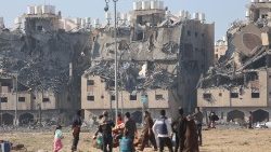 Building lie in ruin as Palestinians carry their belongings following Israeli strikes on residential buildings in Khan Younis