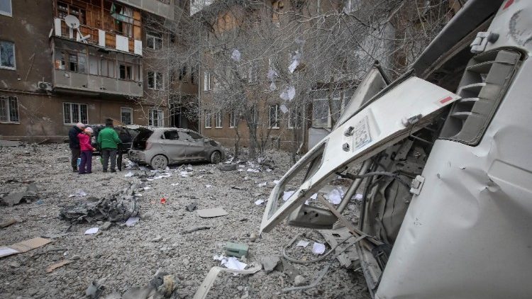 Moradores locais ficam perto de seu prédio de apartamentos e carros danificados durante um ataque de míssil russo, em meio ao ataque da Rússia à Ucrânia, em Kharkiv, Ucrânia, 8 de dezembro de 2023. REUTERS/Vyacheslav Madiyevskyy