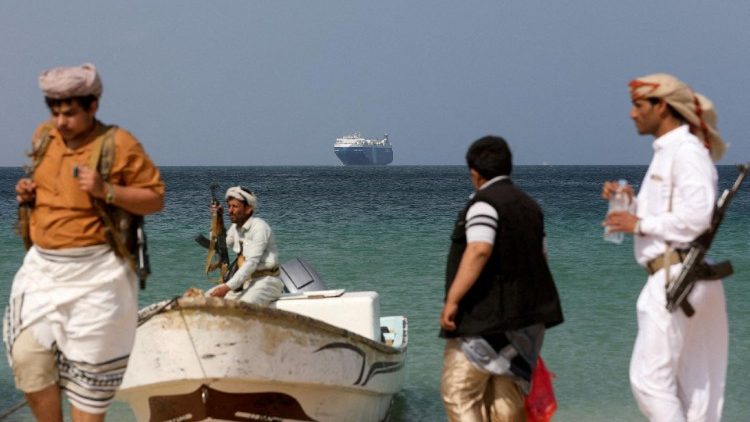Uomini armati in piedi sulla spiaggia mentre la nave commerciale Galaxy Leader, sequestrata dagli Houthi dello Yemen il mese scorso, è ancorata al largo della costa di al-Salif