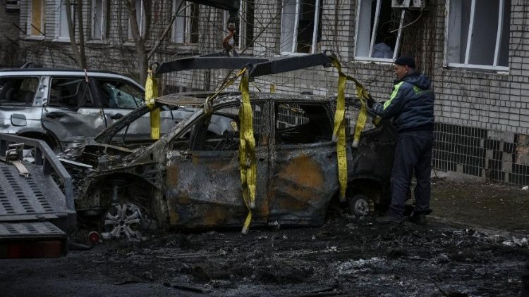 Um trabalhador comunitário prepara um carro danificado para ser rebocado, perto de um prédio residencial danificado durante um ataque de drone russo, em meio ao ataque da Rússia à Ucrânia, em Dnipro, Ucrânia, 7 de janeiro de 2024. REUTERS/Mykola Synelnykov