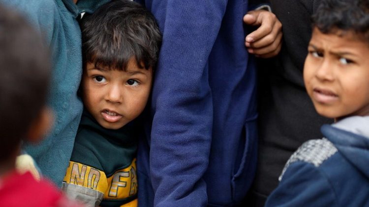 Crianças palestinas esperam para receber comiida em  Rafah. Foto: Vatican Media