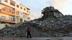 जबलेह में पिछले साल आए घातक भूकंप के बाद एक क्षतिग्रस्त इमारत के मलबे के पास से गुजरता एक व्यक्ति