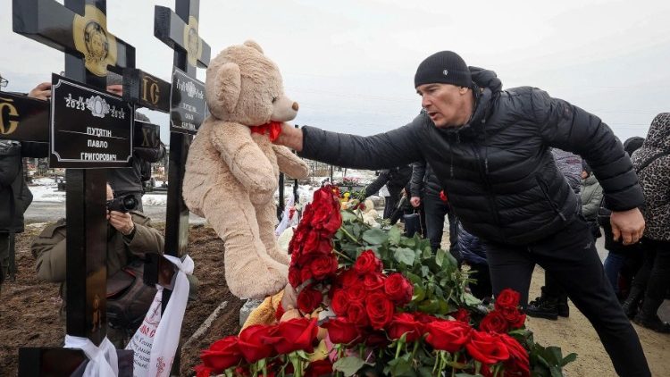 Um homem coloca um brinquedo em um túmulo durante a cerimônia fúnebre de uma família de dois adultos e três crianças, residentes locais que foram mortos na sexta-feira, 9 de fevereiro, em sua casa que pegou fogo em um ataque de drone russo, em meio ao ataque da Rússia à Ucrânia, em Kharkiv, Ucrânia, 12 de fevereiro de 2024. REUTERS/Vyacheslav Madiyevskyy