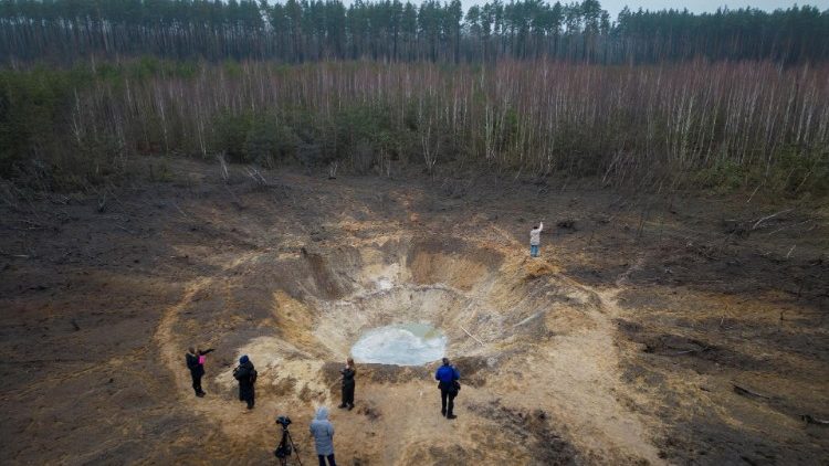Pessoas ficam ao redor de uma cratera criada por um ataque de míssil russo, em meio ao ataque da Rússia à Ucrânia, na vila de Buda-Babynetska, nos arredores de Bucha, perto de Kiev, Ucrânia, 15 de fevereiro de 2024. REUTERS/Thomas Peter