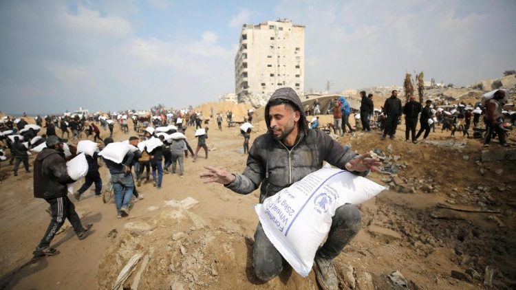 Palestyńczycy noszący worki z mąką otrzymane w ramach pomocy humanitarnej w Strefie Gazy, 19 lutego 2024 r.