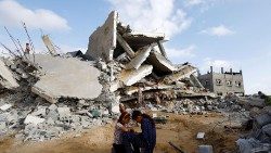 Niños palestinos sentados junto al lugar de un ataque israelí contra una casa, en Rafah, en el sur de la Franja de Gaza, 21 de abril de 2024.