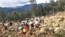 People carry bags in the aftermath of a landslide in Enga Province,