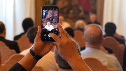 An audience participants holds up a smartphone to photograph the Pope