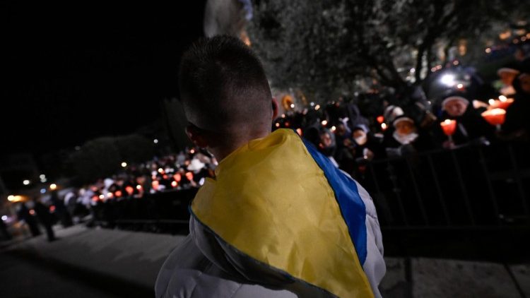 Un giovane con un foulard con i colori della bandiera ucraina porta la croce