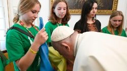 Pope Francis kisses the Ukrainian flag at a meeting with young Ukrainian pilgrims in Lisbon