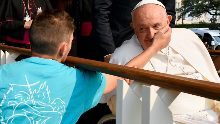 A young man caresses Pope Francis' cheek as he greets pilgrims in Fatima