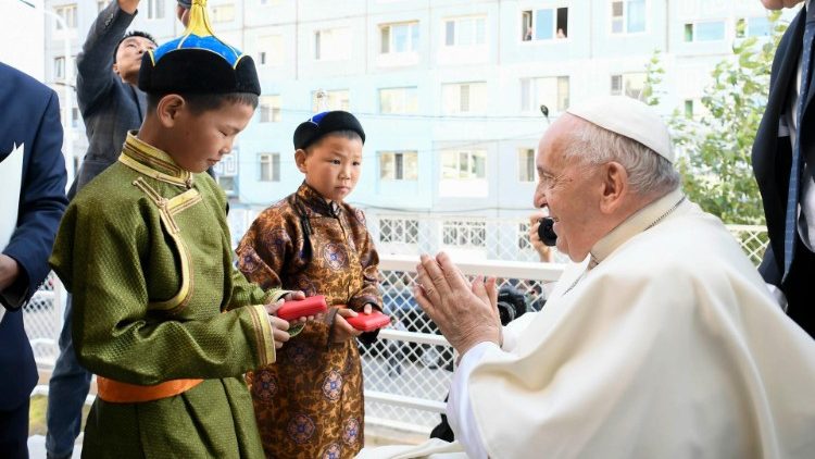 Pope Francis receives a bouquet of flowers from two young Mongolian boys