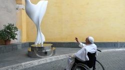 Papst Franziskus mit einer Friedenstauben-Skulptur