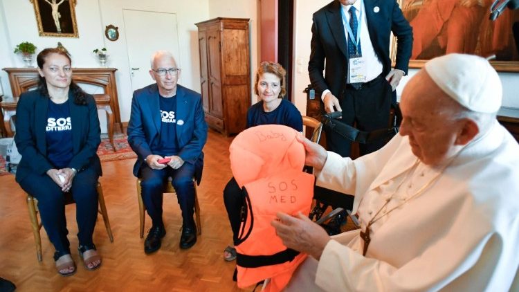 Pope Francis holds a lifejacket