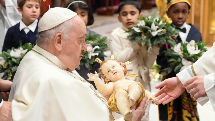 Papa Francesco porta l'immagine del Bambinello al presepe, intorno, un gruppo di bambini