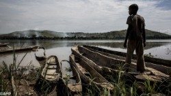 Un enfant et des pirogues au bord du fleuve Congo. 