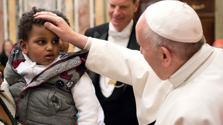 La caricia del Papa a un niño migrante.